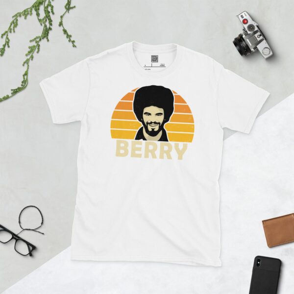 A white T-shirt with a bold portrait of football legend George Berry. The image is set against a Golden Orange sunburst background with the name "BERRY" in light yellow underneath.
