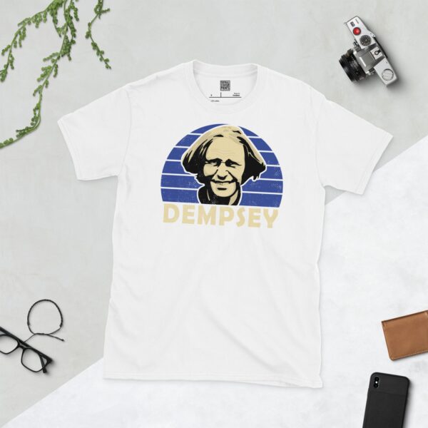 A white T-shirt with a bold portrait of football legend John Dempsey. The image is set against a blue sunburst background with the name "DEMPSEY" in light yellow underneath.
