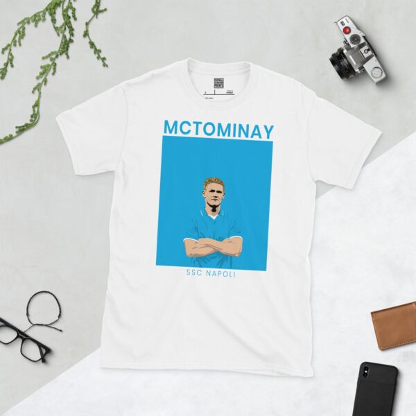 A white T-shirt with a contemporary graphic of Scott McTominay in a light blue top, with the text "MCTOMINAY" above and "SSC NAPOLI" below the image.