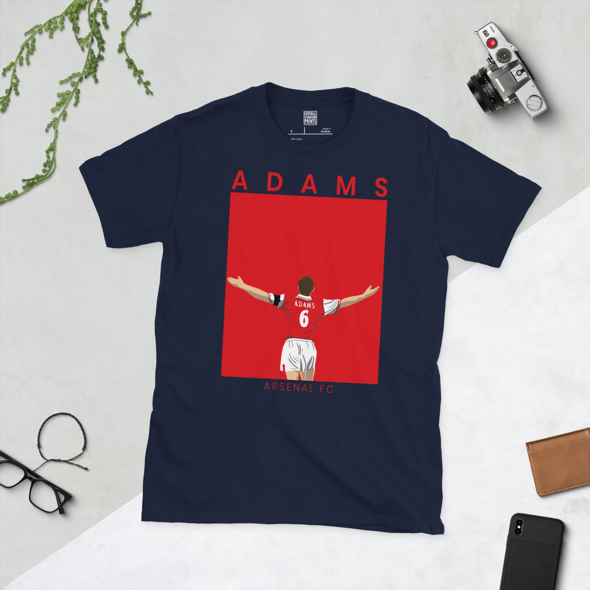 A navy T-shirt displaying a stylised illustration of Tony Adams, the former Arsenal captain, in his number 6 kit celebrating. The name "ADAMS" is above his portrait and "ARSENAL FC" is written beneath the image.