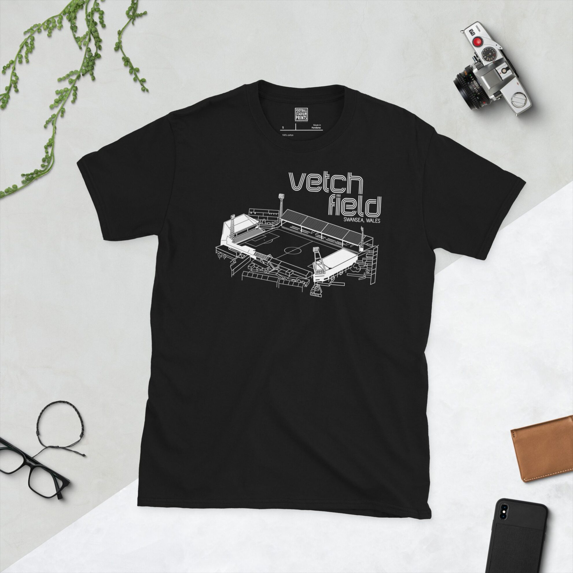 A black T-shirt featuring a white line art graphic of Vetch Field stadium, with "VETCH FIELD" and "SWANSEA, WALES" text above the stadium illustration.