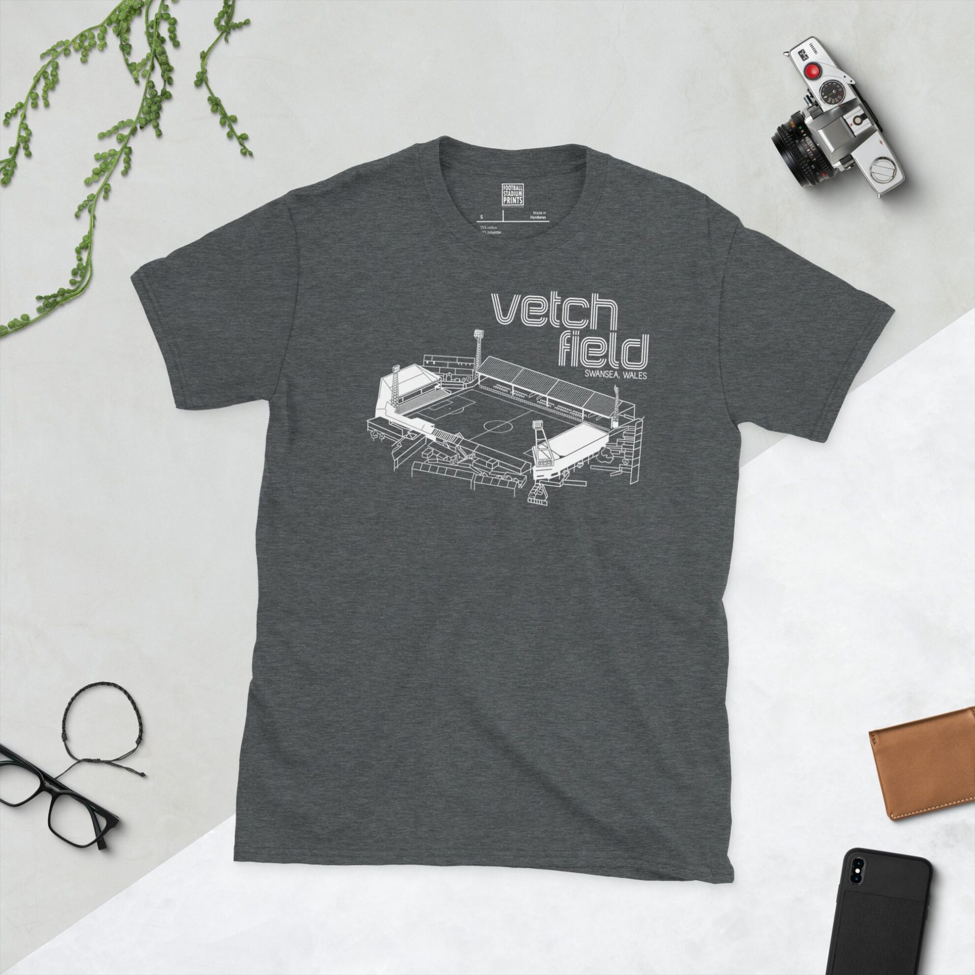 A dark heather T-shirt displaying a white line art graphic of Vetch Field stadium, including floodlights and stands, with its name prominently displayed above.