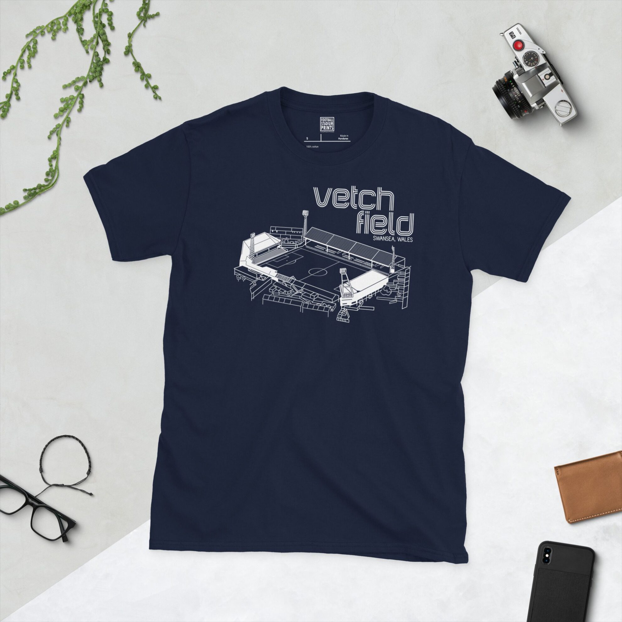 A navy T-shirt showcasing a white line art graphic of the Vetch Field football stadium, former home of Swansea City AFC, with "VETCH FIELD" clearly visible.