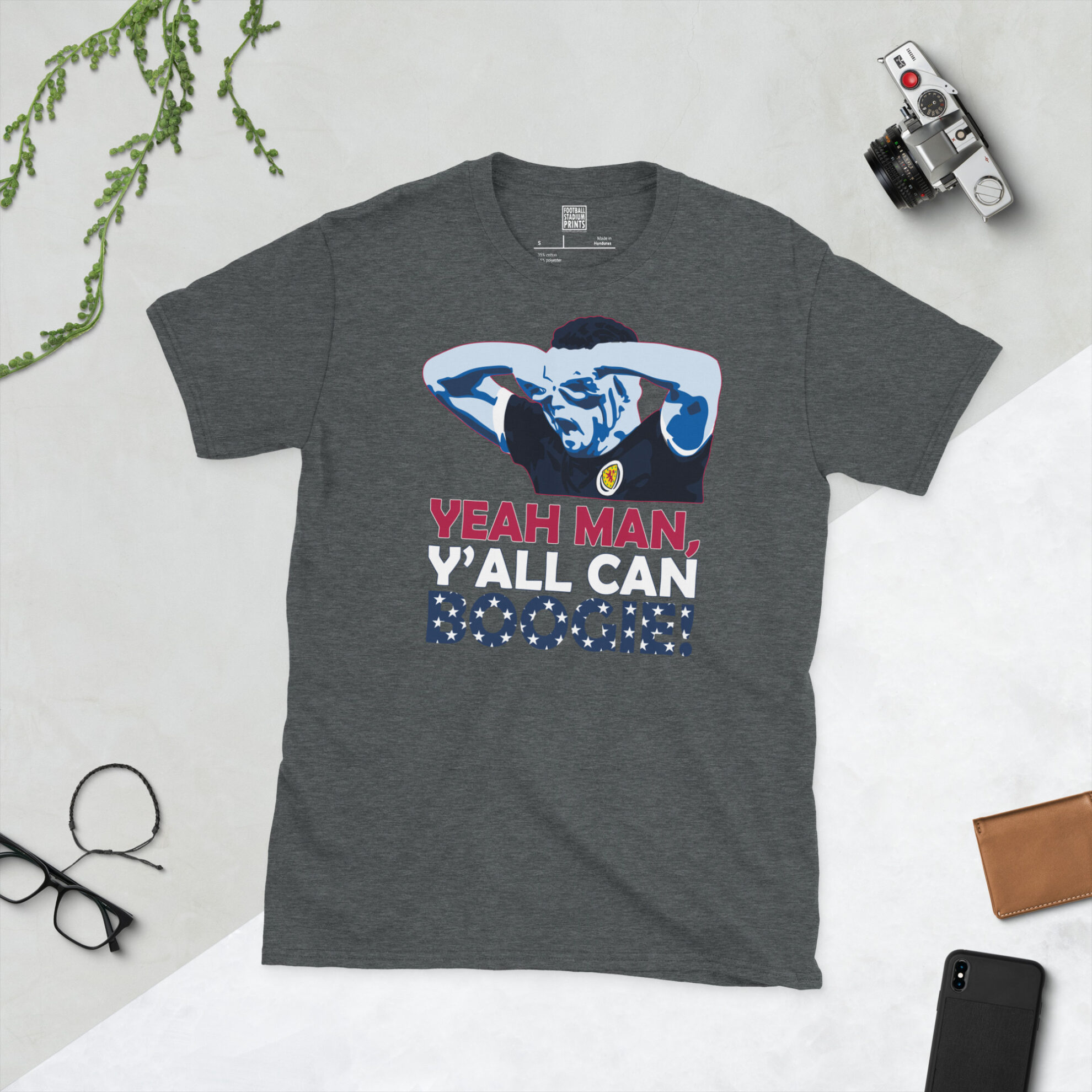 A dark heather T-shirt showing a clean, modern graphic of John McGinn, the Scotland star, performing the specs celebration with "Yeah man, y'all can boogie" prominent on the design.