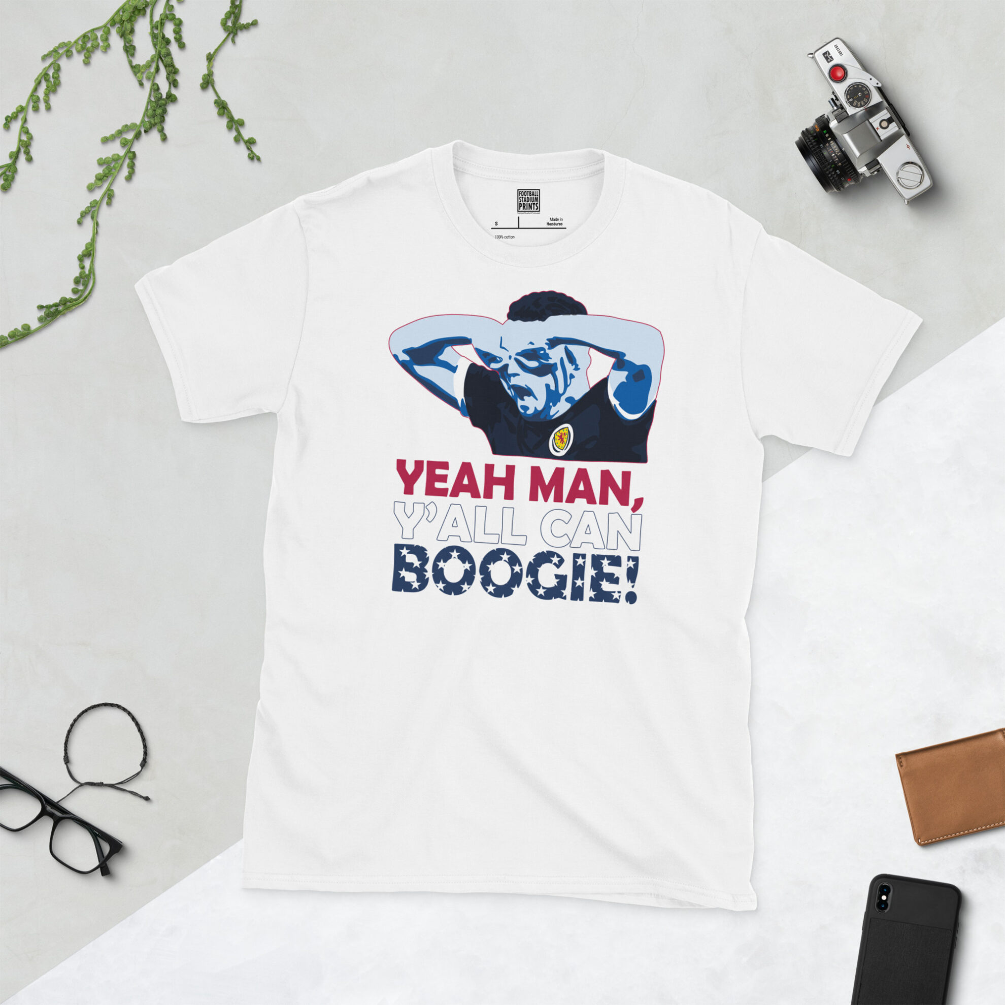 A white T-shirt with a bold graphic of Scotland hero John McGinn doing the "goggles" celebration, along with the North American-themed anthem twist.