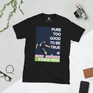 A black T-shirt featuring a dynamic graphic of Scotland's Kieran Tierney scoring a goal. The quote "PURE TOO GOOD TO BE TRUE KINNA HING" is printed on the design, commemorating the World Cup 2026 qualification.