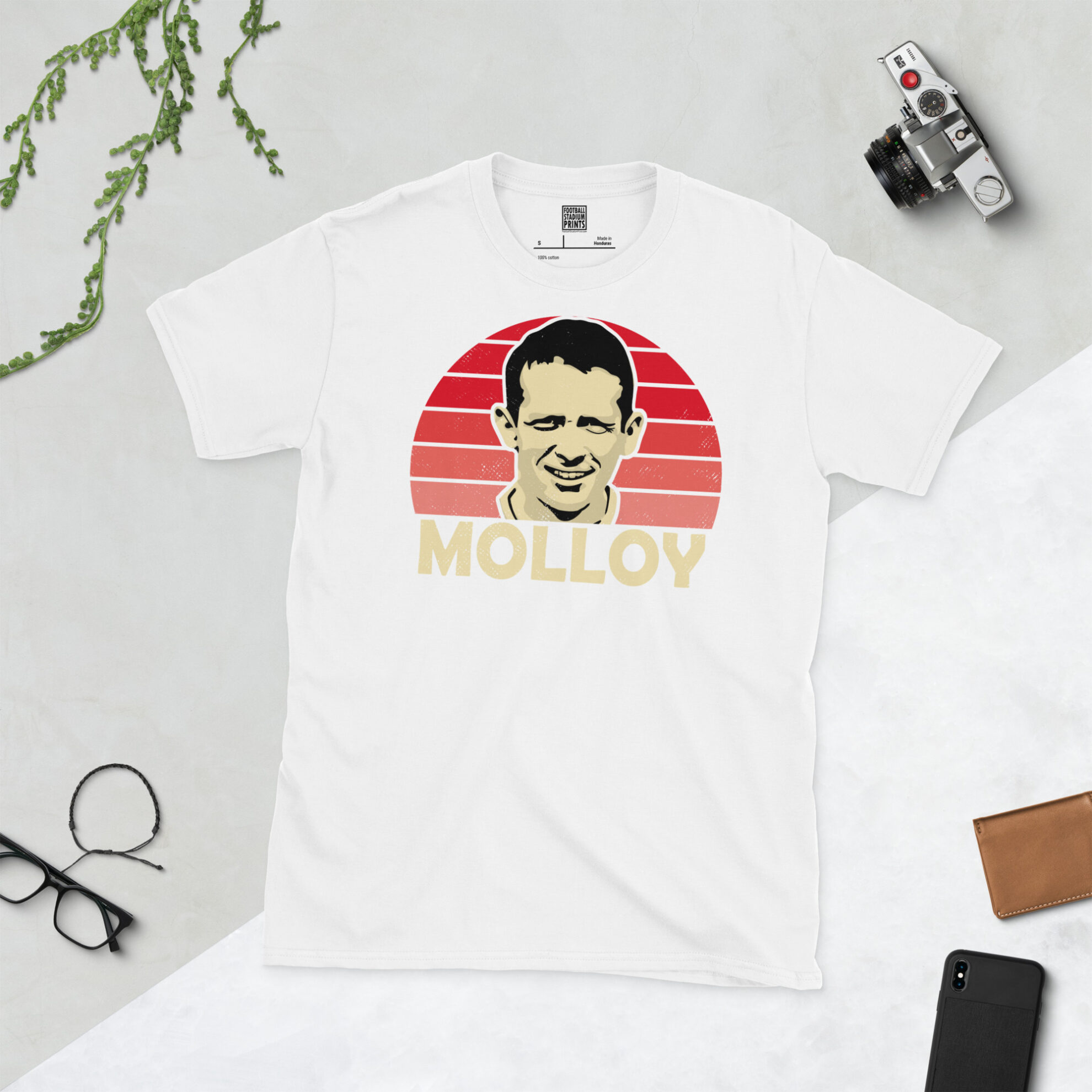 A white T-shirt with a bold, retro graphic of football legend Craig Molloy. The image is set against a red sunburst background and the name "MOLLOY" is in light yellow underneath.