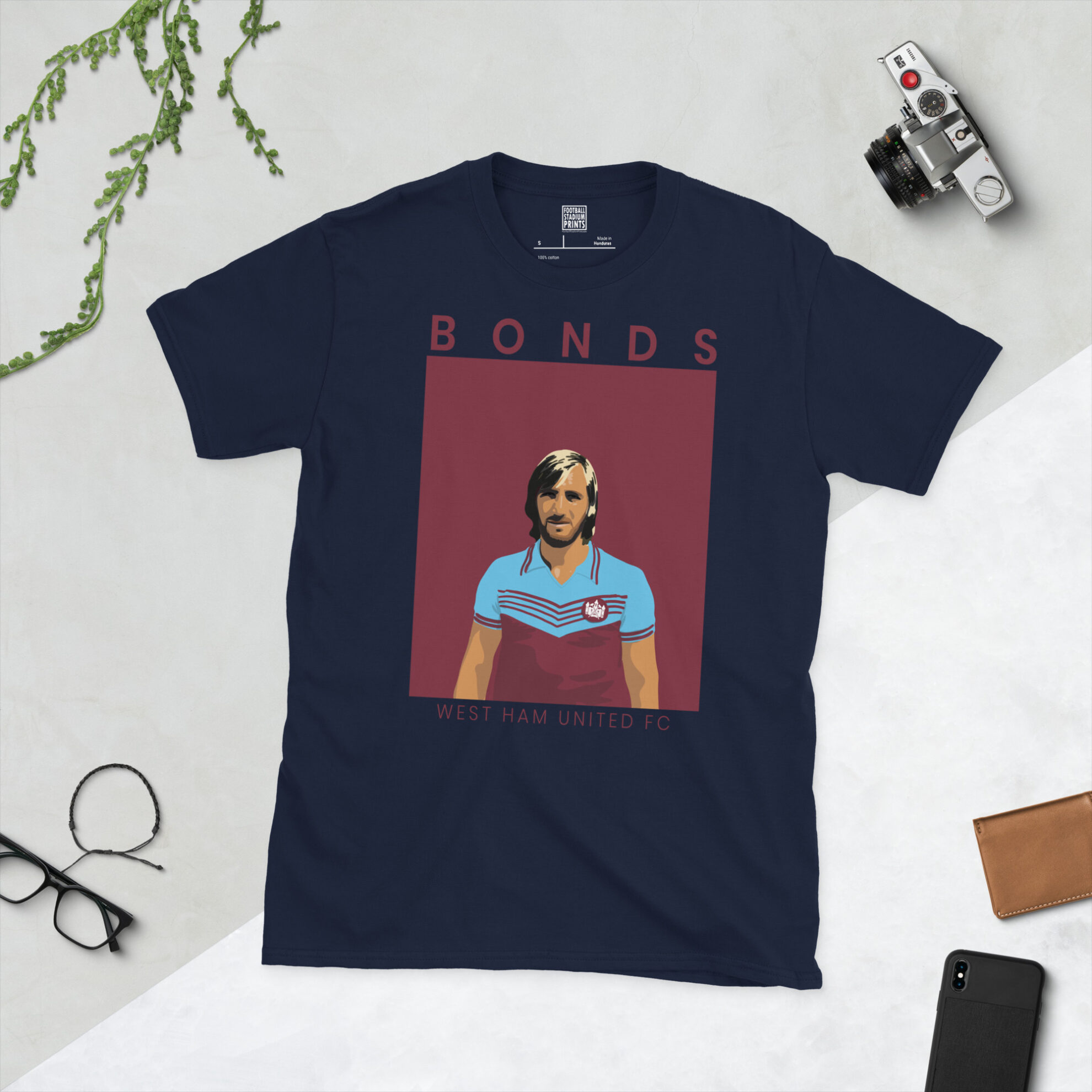 A navy T-shirt displaying an artistic illustration of Billy Bonds, the West Ham captain. The graphic is backed by a claret sunburst and the name "BONDS" appears underneath in light yellow.
