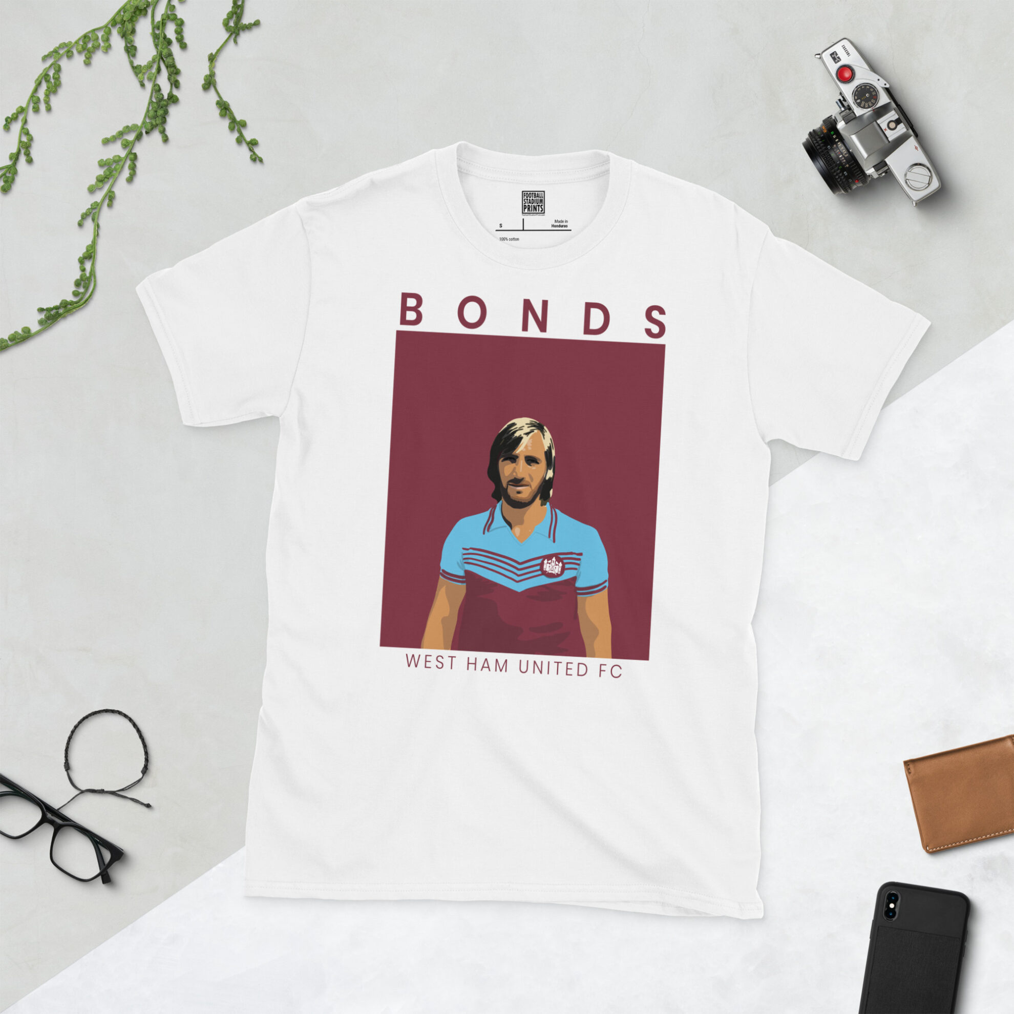 A white T-shirt with a bold, retro portrait of football legend Billy Bonds. The image is set against a claret sunburst background and the name "BONDS" is in light yellow underneath.