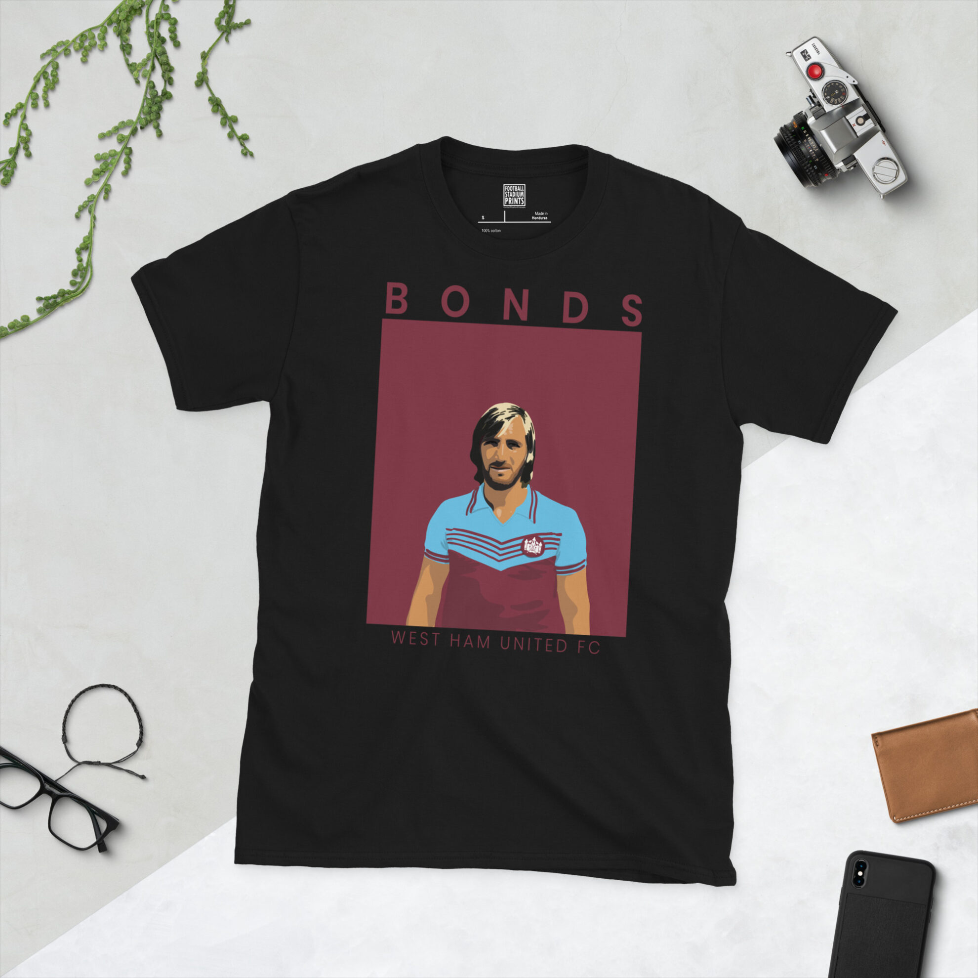 A black T-shirt featuring a stylised, distressed graphic of West Ham United legend Billy Bonds' profile, set against a claret striped sunburst background. The name "BONDS" is printed in light yellow below the portrait.