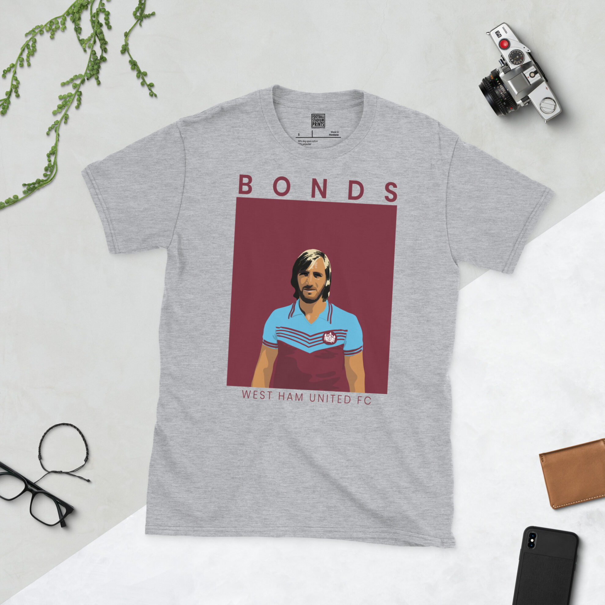A sports grey T-shirt featuring a unique graphic of West Ham's Billy Bonds. The image is backed by a claret sunburst and the text "BONDS" is printed in light yellow below the portrait.