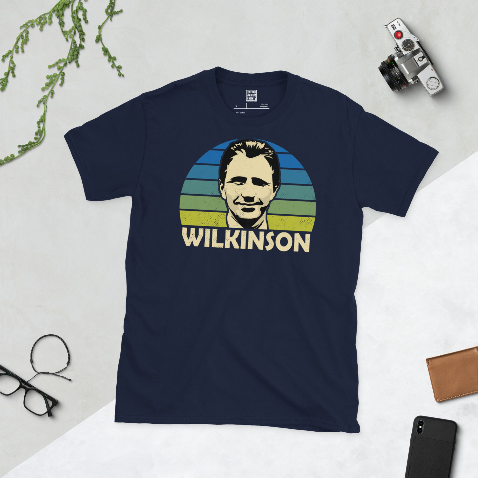 A navy T-shirt displaying an artistic illustration of Howard Wilkinson, the 1992 title-winning manager. The graphic features a blue to yellow sunburst and the surname "WILKINSON" appears underneath in white.