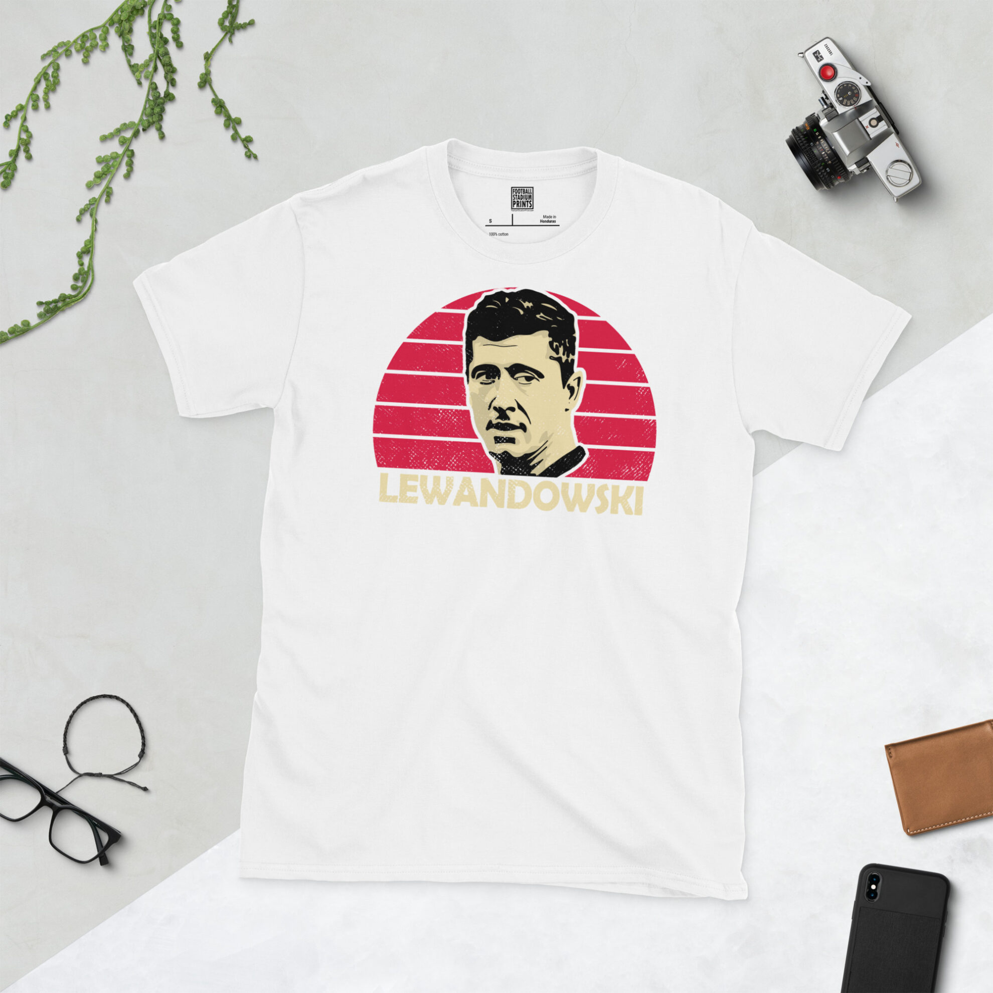 A white T-shirt with a bold, retro graphic of football legend Robert Lewandowski. The image is set against a red sunburst background and the name "LEWANDOWSKI" is in light yellow underneath.