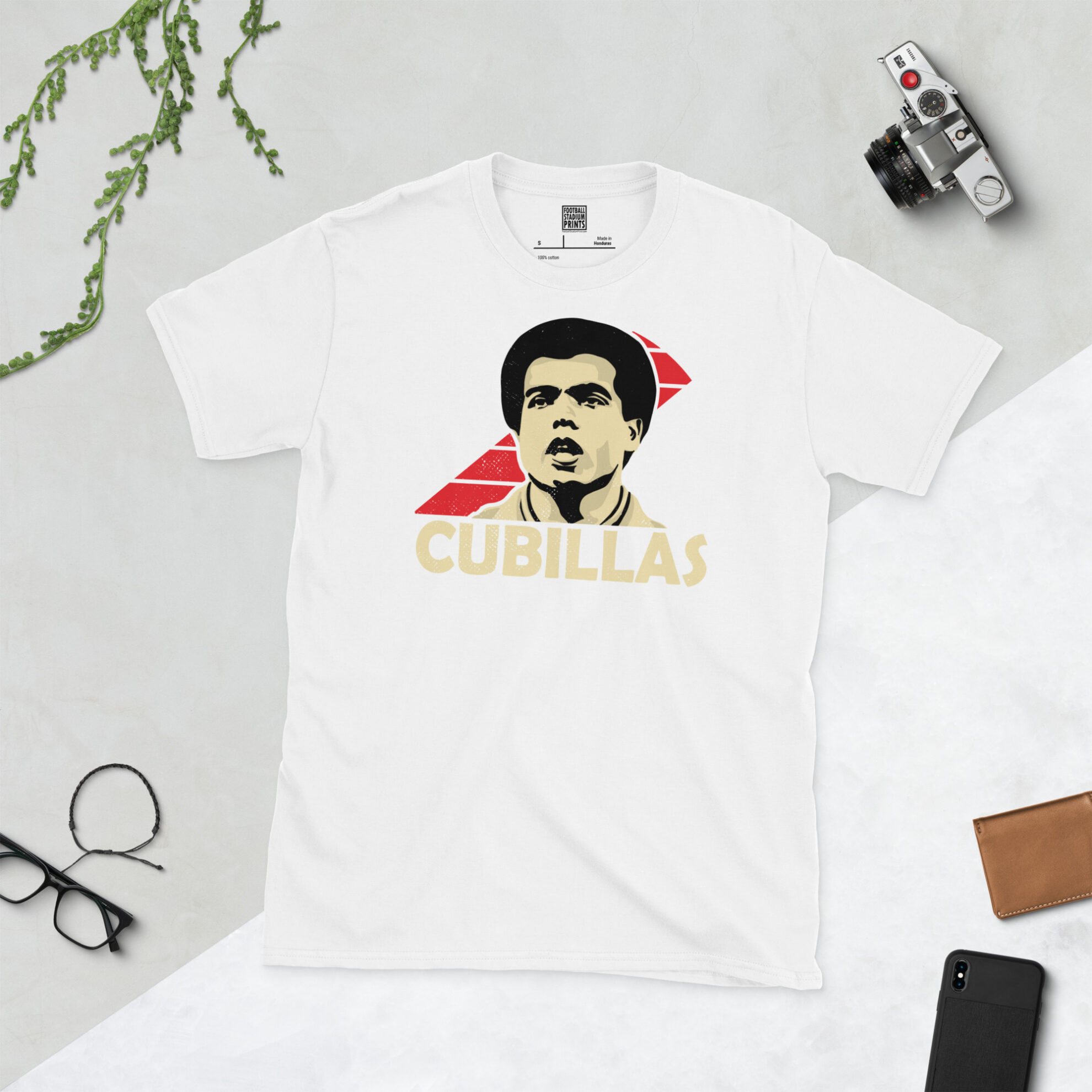A white T-shirt with a bold, retro graphic of football legend Teófilo Cubillas. The image is set against a white and red sash sunburst background and the name "CUBILLAS" is in light yellow underneath.
