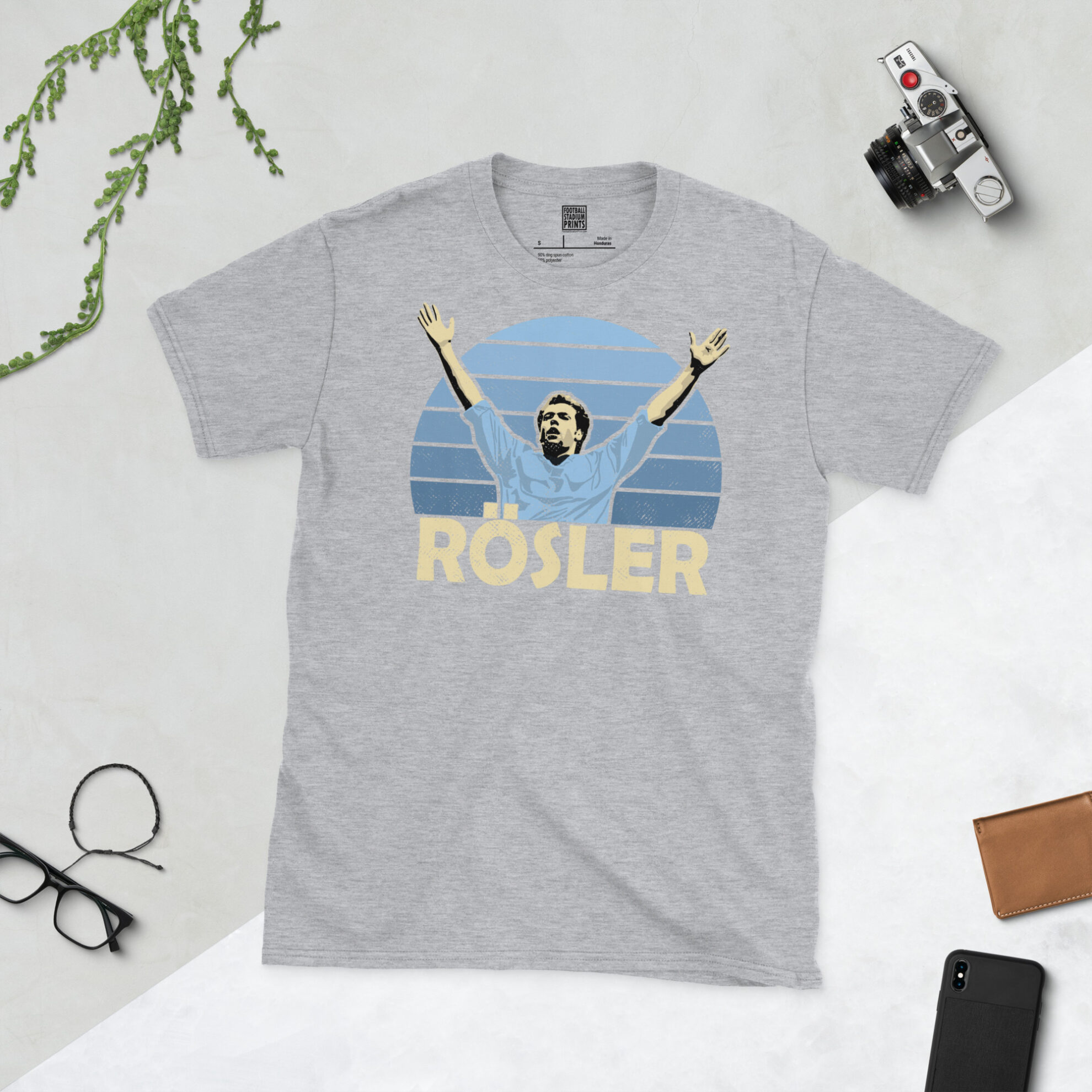 A sports grey T-shirt featuring a unique graphic of Uwe Rosler. The image is backed by a blue sunburst and the text "ROSLER" is printed below the portrait in light yellow.