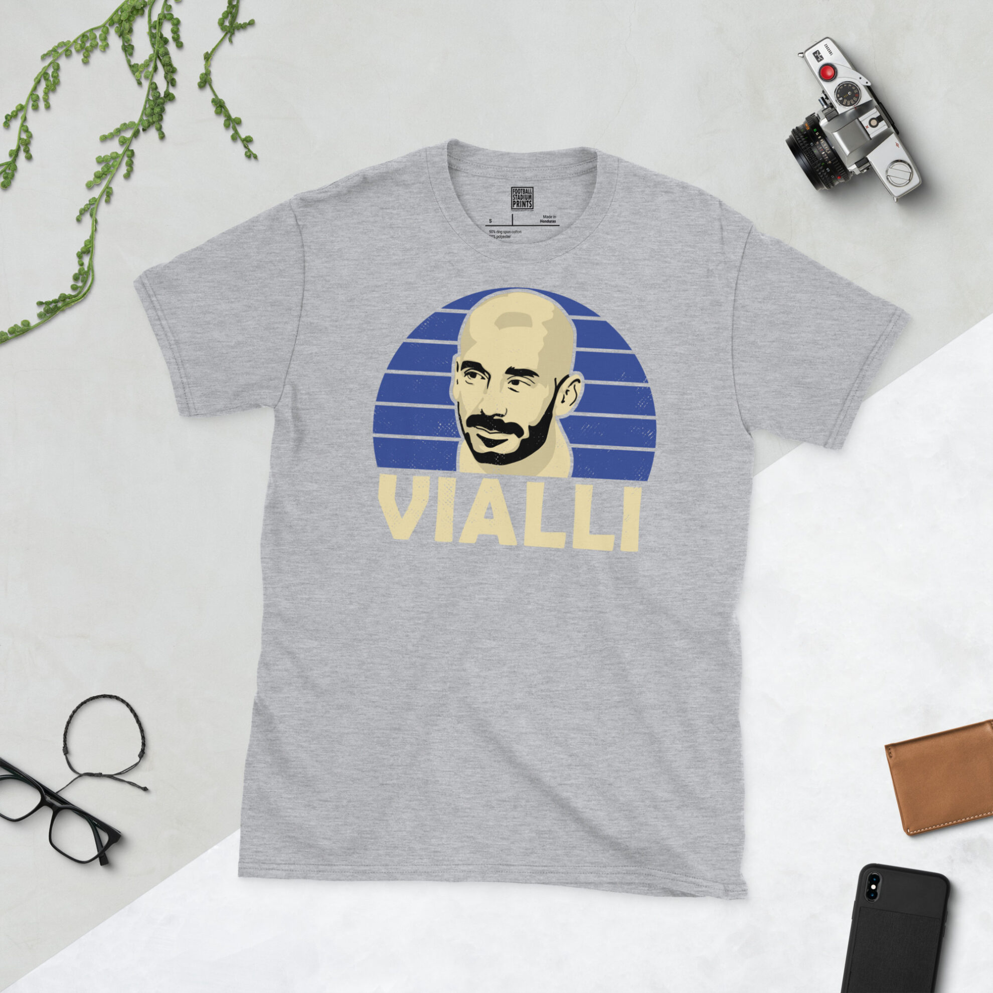 A sports grey T-shirt featuring a unique graphic of Gianluca Vialli. The image is backed by a blue sunburst and the text "VIALLI" is printed below the portrait in light yellow.