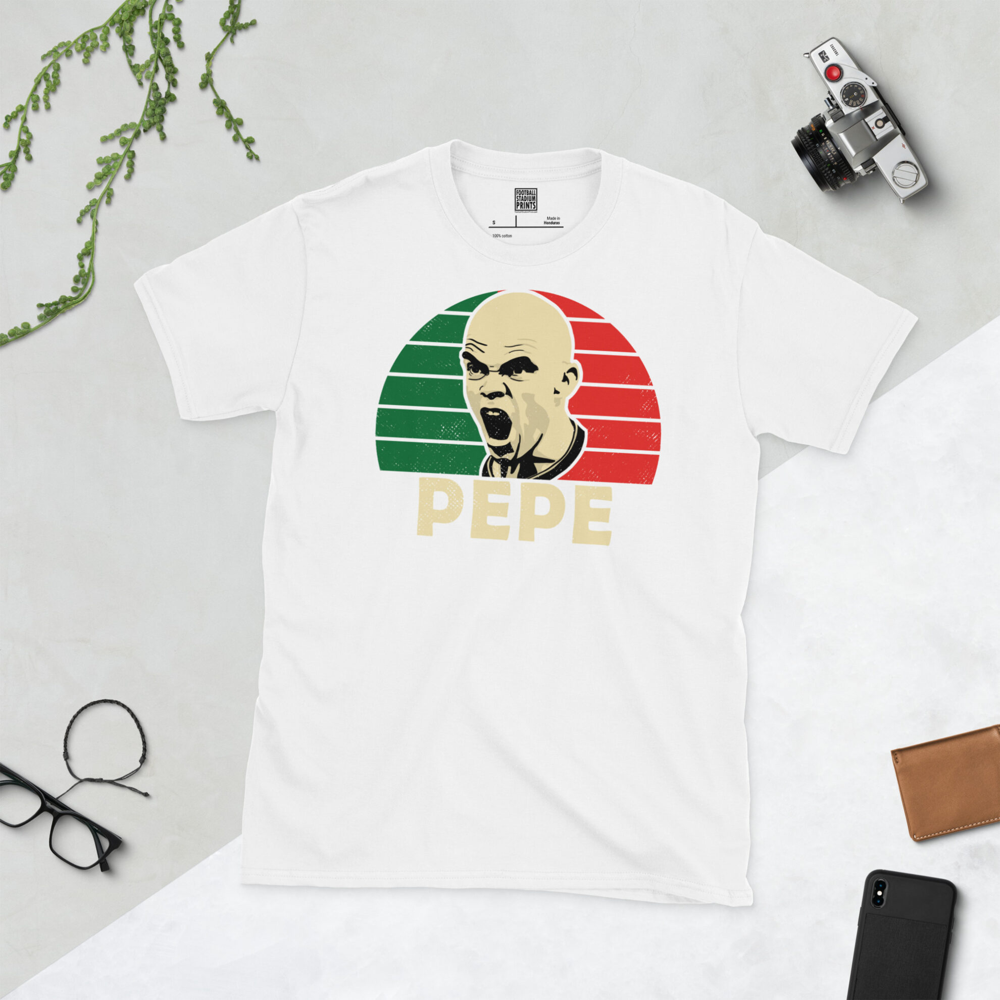 A white T-shirt with a bold, retro graphic of football icon Pepe. The image is set against a green and red flag-style sunburst background and the name "PEPE" is printed underneath.