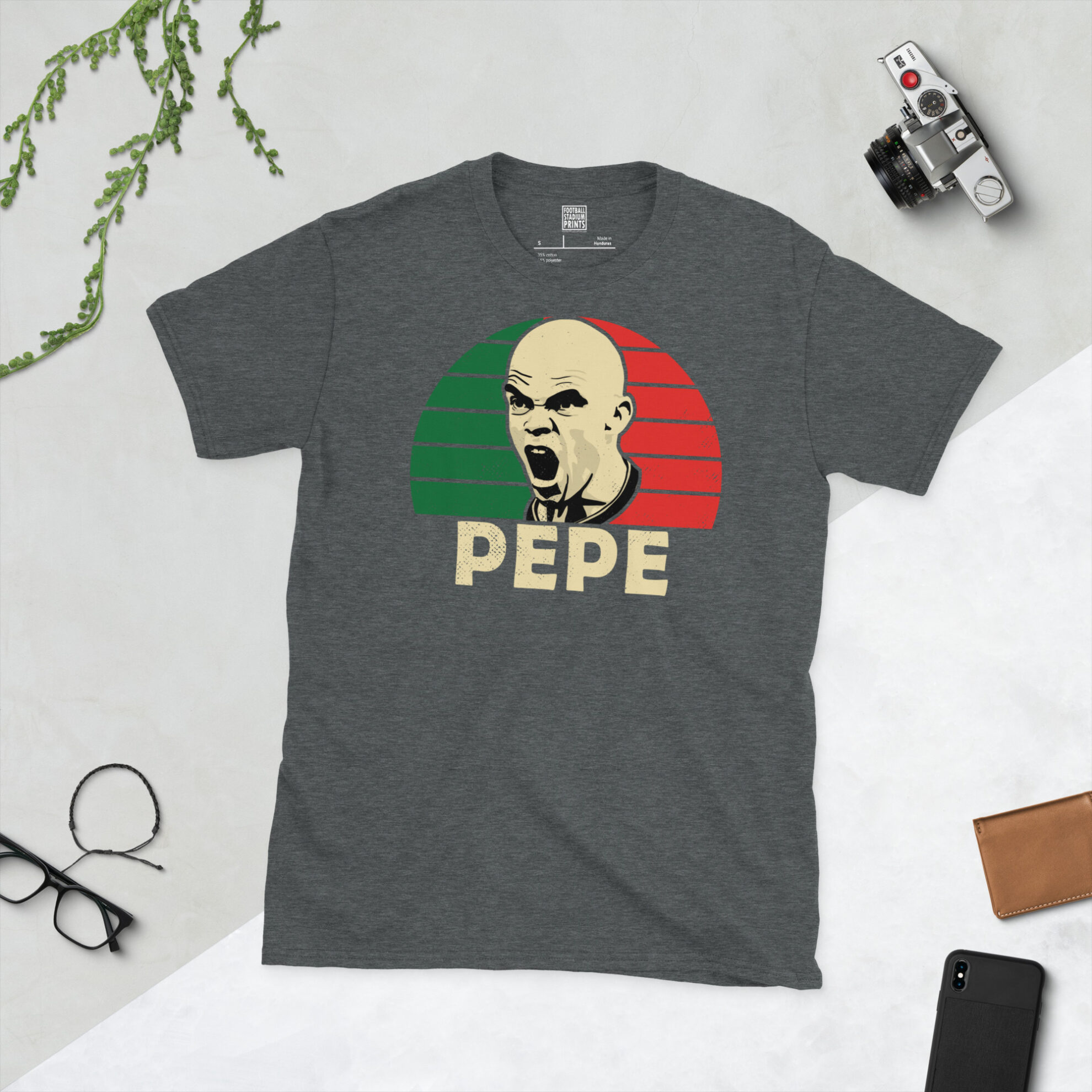 A dark heather T-shirt showing a clean, modern portrait of Pepe, the Portuguese international, with "PEPE" printed below the image on a green and red sunburst background.
