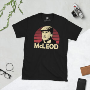 A black T-shirt featuring a stylised graphic of Kilnockie FC manager Gordon McLeod. The portrait shows him in a flat cap against a maroon sunburst, with the name "McLEOD" below.
