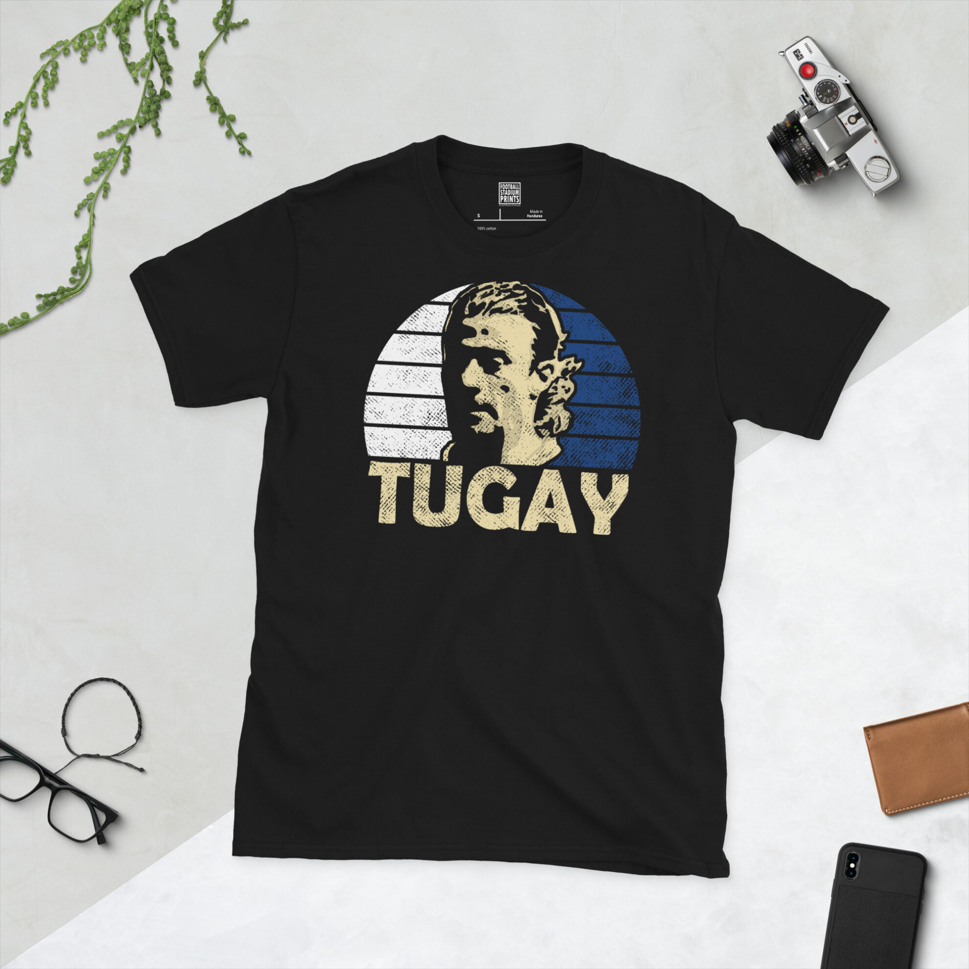 A black T-shirt featuring a stylised graphic of Blackburn Rovers legend Tugay Kerimoğlu. The portrait is backed by a blue and white sunburst, with the name "TUGAY" printed below.