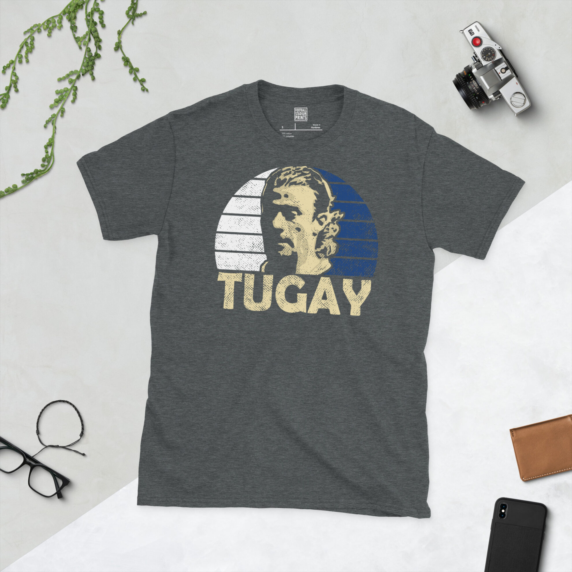 A dark heather T-shirt showing a clean portrait of Tugay, the Rovers icon, with "TUGAY" printed below the image on a blue and white sunburst.
