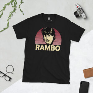 A premium black T-shirt featuring a distressed claret sunburst graphic of Northampton Town legend Graham Reed, with "RAMBO" typography below.