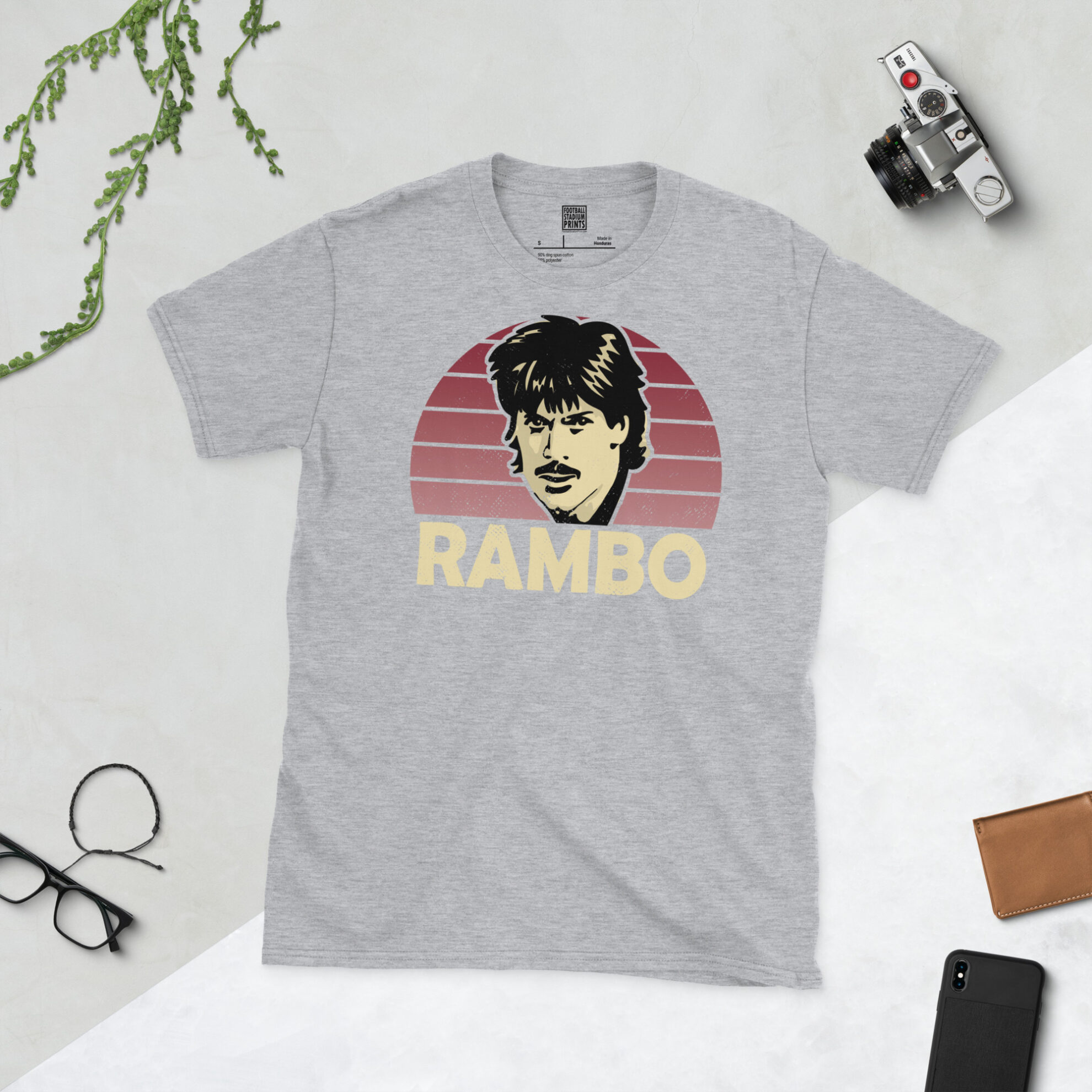 A sports grey T-shirt featuring a claret sunburst design of Graham Reed, titled "RAMBO" in bold block lettering.