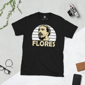 A premium black T-shirt featuring a distressed white sunburst graphic of Swansea City defender Chico Flores with "FLORES" in bold lettering.