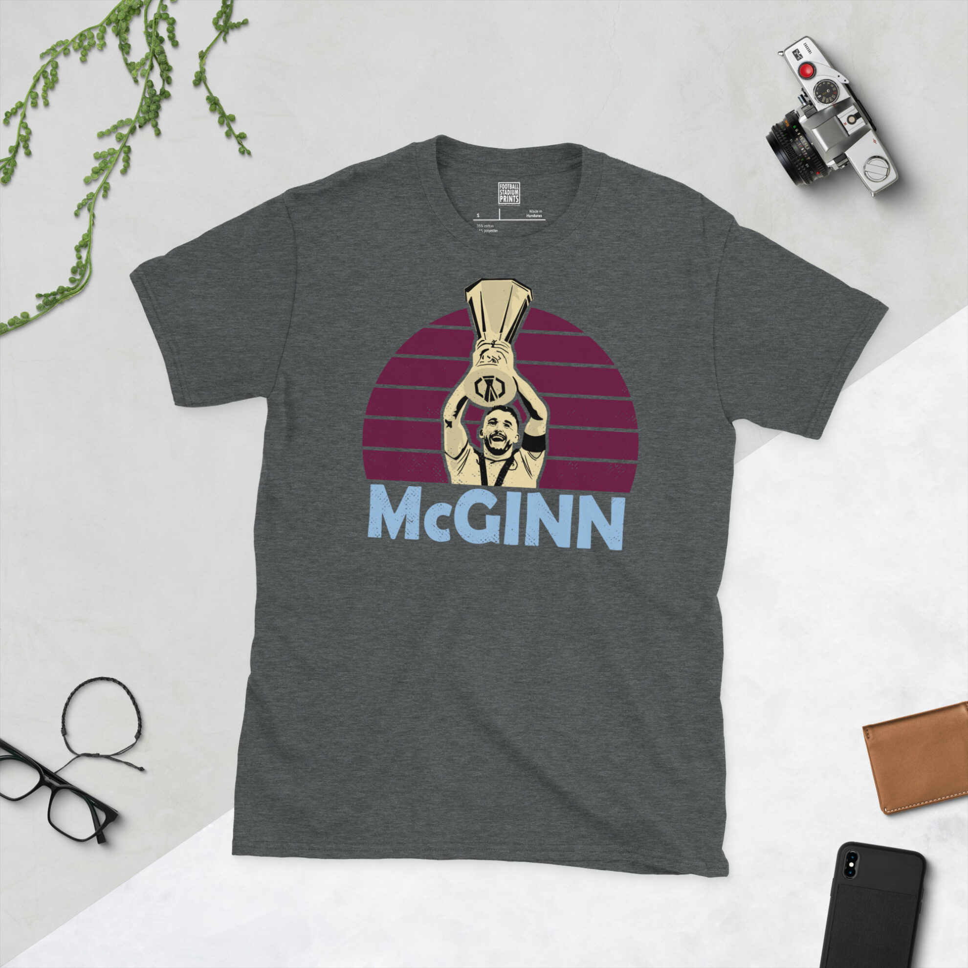 A dark heather grey T-shirt with a vintage-style graphic of John McGinn raising the European trophy, finished with his name in sky blue.