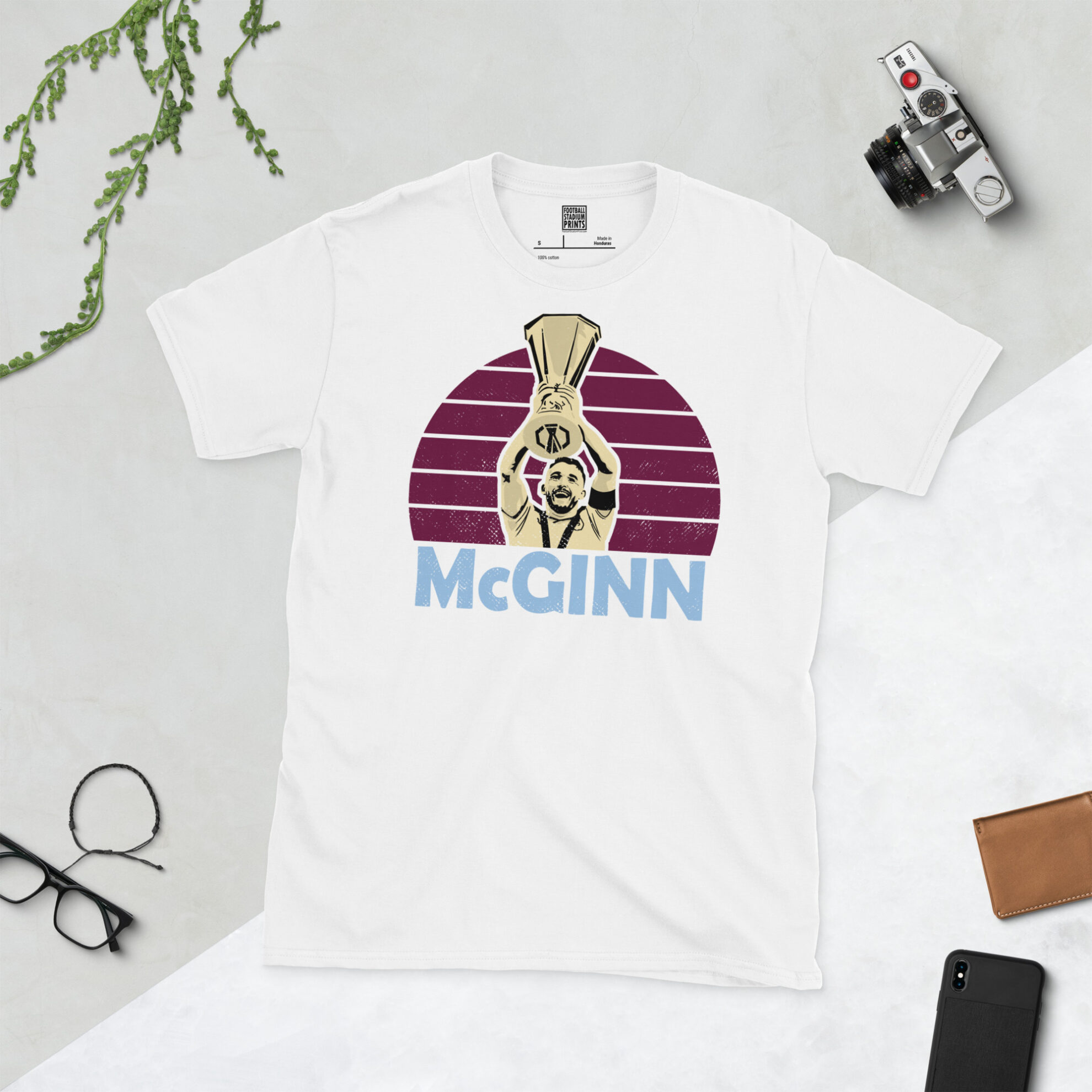 A clean white T-shirt featuring a high-definition distressed print of John McGinn lifting the Europa League cup, a tribute to the 2026 champions.