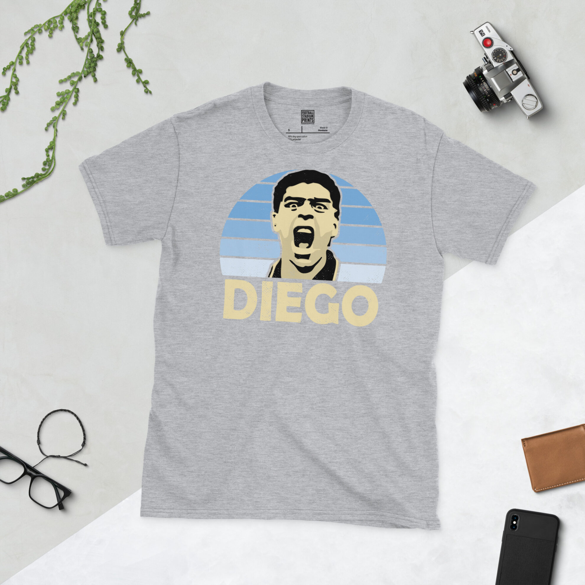 A sports grey T-shirt featuring a bold sky blue fade sunburst design of Diego Maradona's iconic 1994 goal celebration.
