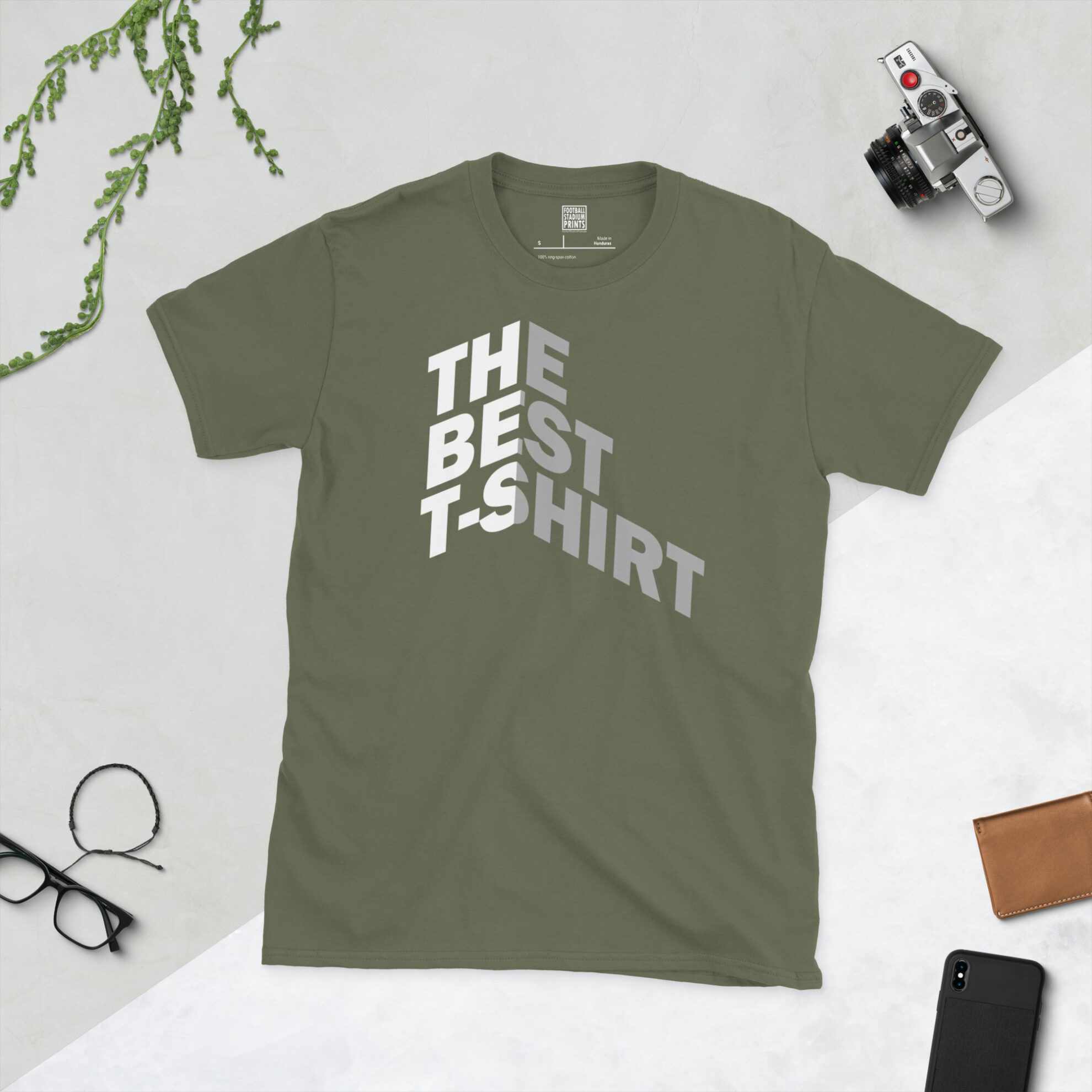 A military green t-shirt with Bold white and gray text reading THE BEST T-SHIRT folded around a 3D isometric corner against a black background