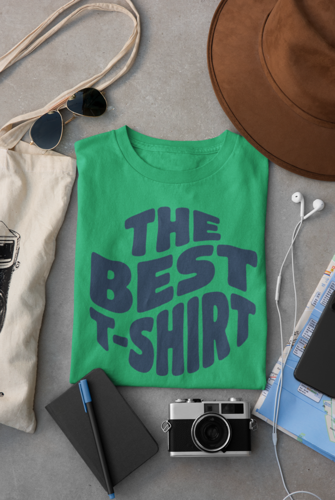 Flat lay of folded green t-shirt printed with dark navy retro wavy text reading The Best T-Shirt