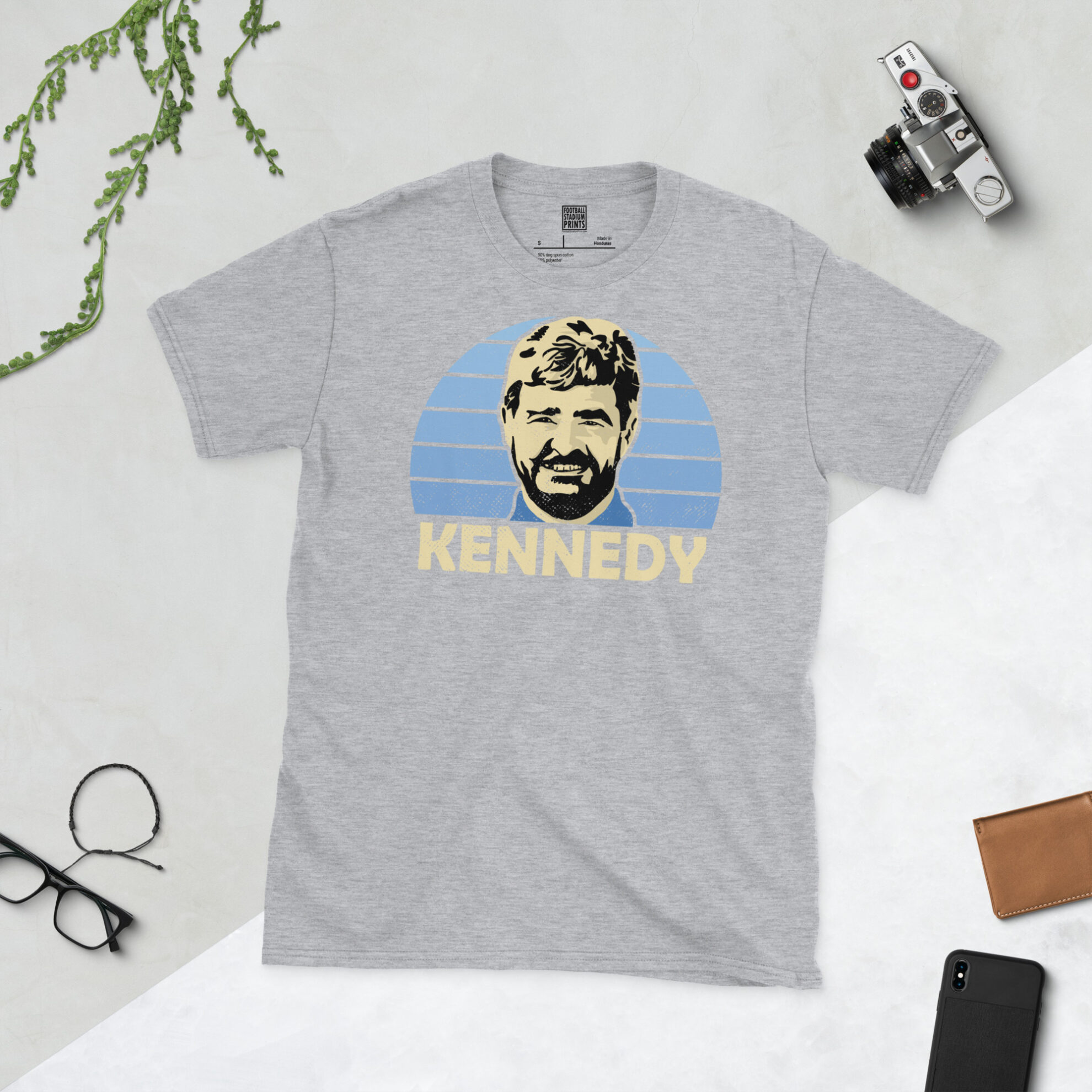 A sports grey T-shirt featuring a bold blue sunburst design of Stewart Kennedy, finished with his surname in a classic retro font.