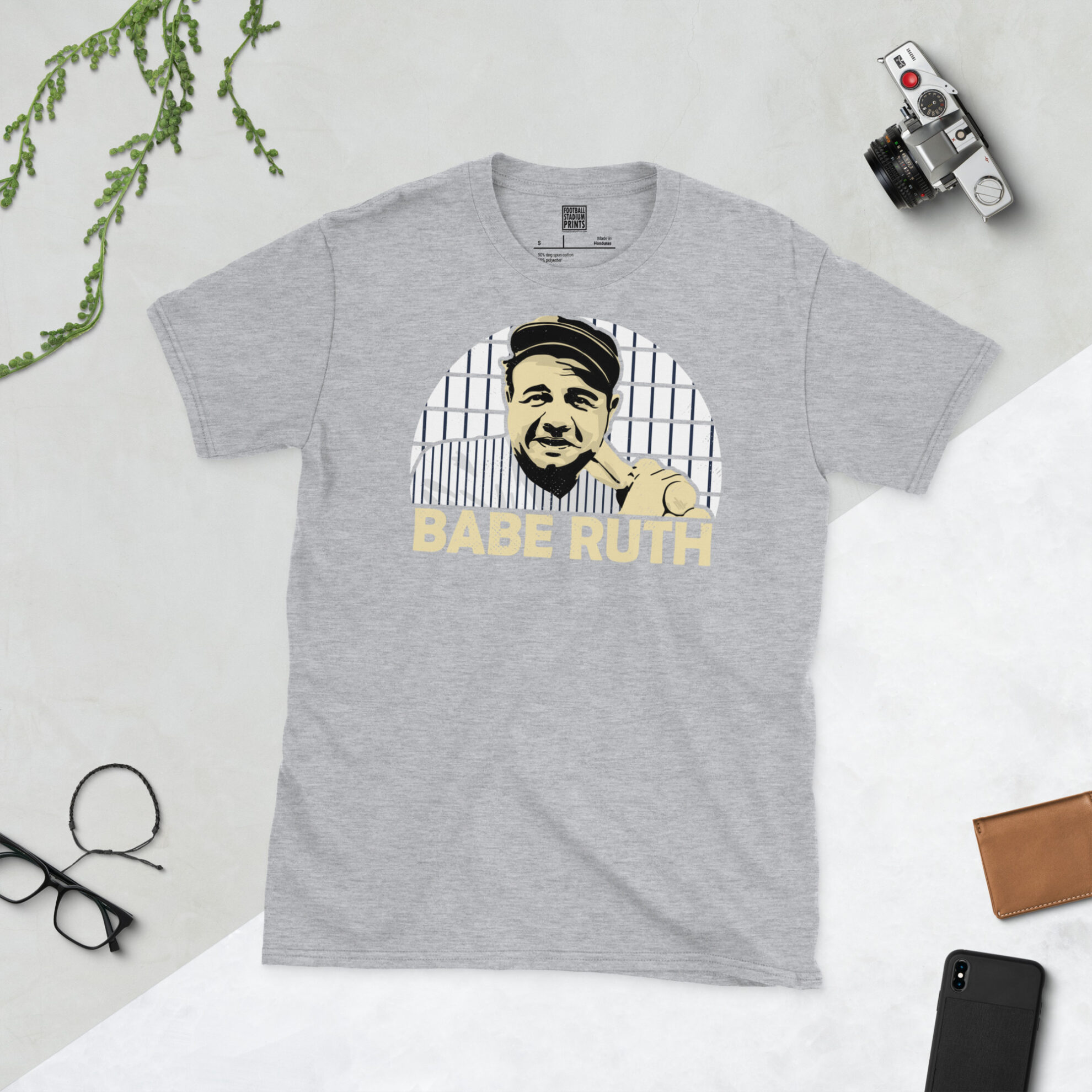A sports grey T-shirt featuring a bold pinstripe sunburst design of Babe Ruth, finished with his name in a classic retro font.